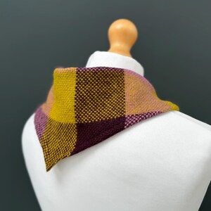 pink, yellow and burgundy triangle neckerchief tie on a mannequin against a dark grey background