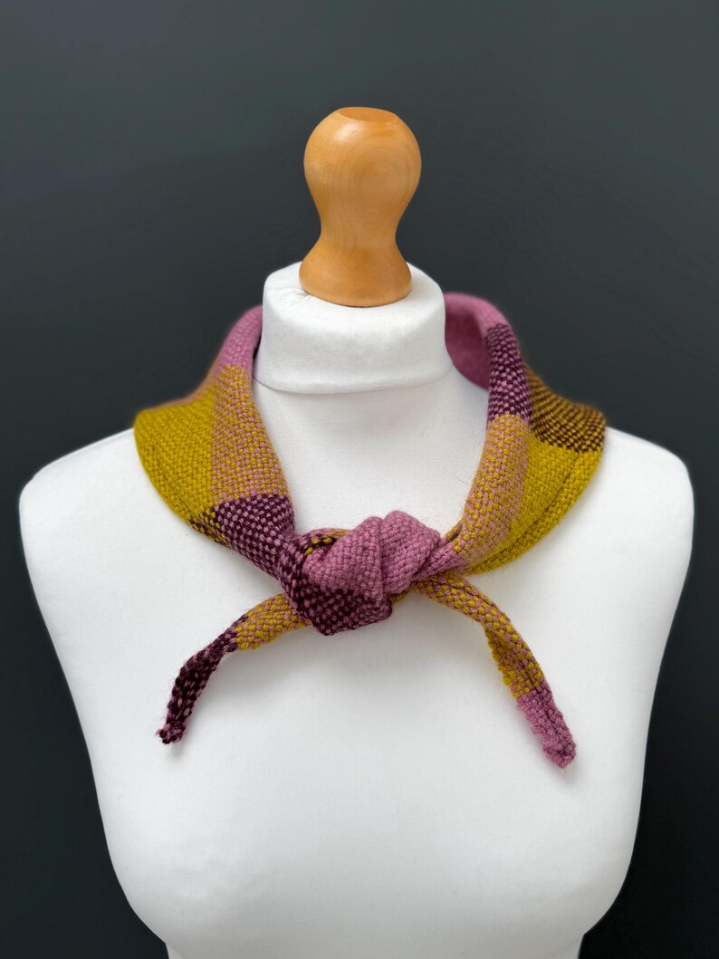 pink, yellow and burgundy triangle neckerchief tie on a mannequin against a dark grey background