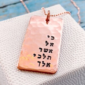 May include: A rose gold necklace with a hammered rectangular pendant featuring Hebrew text. The pendant is engraved with the words "אל תדאג" which translates to "Don't worry".