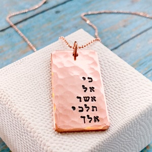 May include: A rose gold necklace with a hammered rectangular pendant featuring Hebrew text. The pendant is engraved with the words "כי אל אשך" which translates to "For God is my light".