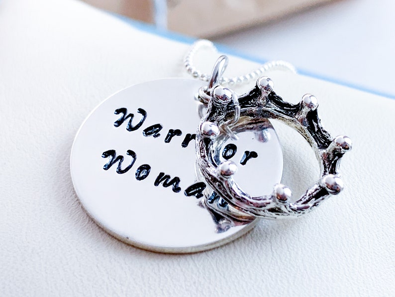 May include: Silver necklace with a round pendant that says "Warrior Woman" and a silver crown charm.