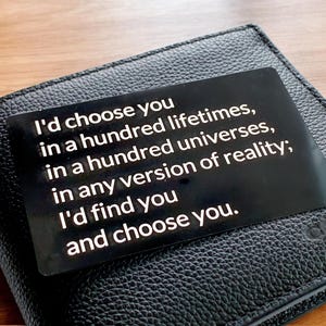 May include: A black leather wallet with a quote printed on a black insert: "I'd choose you in a hundred lifetimes, in a hundred universes, in any version of reality; I'd find you and choose you."