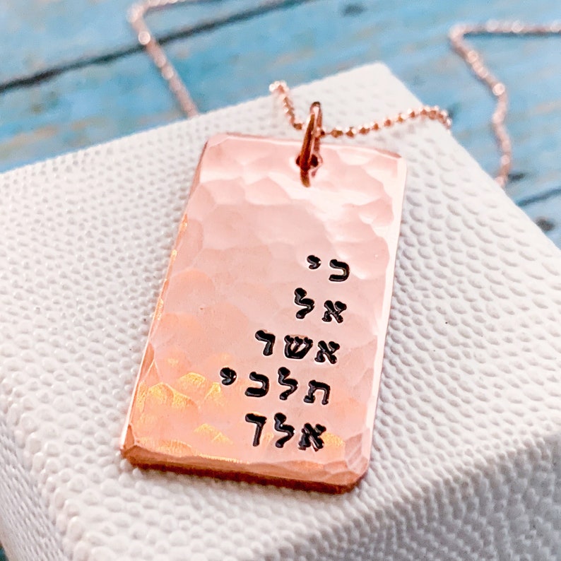 May include: A rose gold necklace with a hammered rectangular pendant featuring Hebrew text. The pendant is engraved with the words "אל תדאג" which translates to "Don't worry".