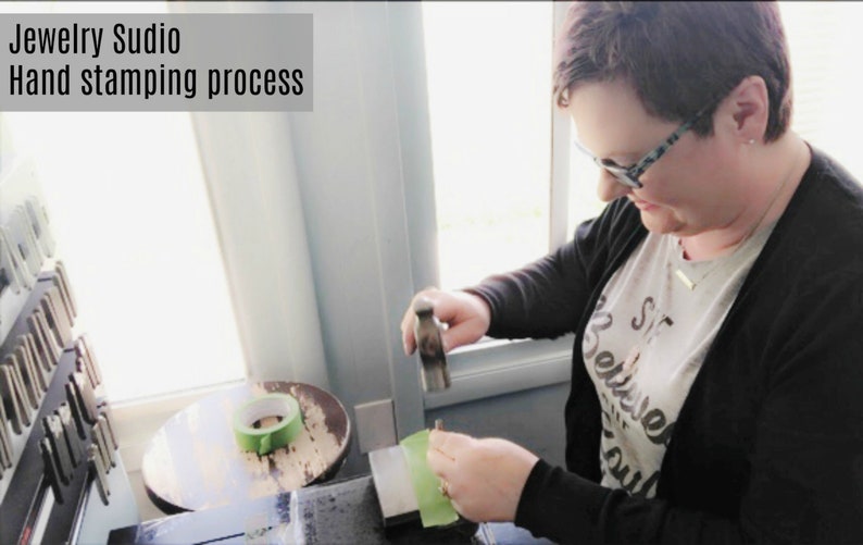 May include: A person hand stamping a piece of metal jewelry with a hammer on a green surface. The text "Jewelry Studio Hand stamping process" is visible at the top of the image.
