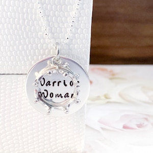 May include: Silver necklace with a round pendant that says "Warrior Woman" in a circle of small beads.