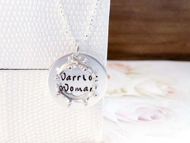 May include: Silver necklace with a round pendant that says "Warrior Woman" in a circle of small beads.