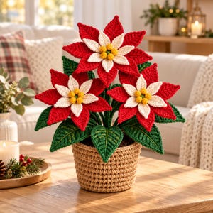 May include: A crocheted poinsettia plant featuring three large red and white flowers with yellow centers and green leaves, all potted in a textured tan crocheted basket. The handcrafted floral arrangement displays intricate yarn stitching.