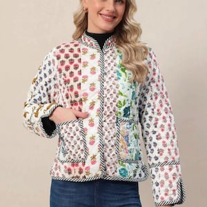 May include: A quilted jacket featuring a patchwork design with various floral and botanical prints in shades of pink, blue, green, and yellow. The jacket has a mandarin collar, long sleeves, two front patch pockets, and black and white striped trim.