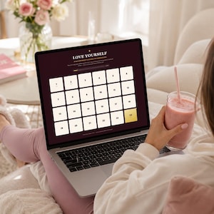 May include: A laptop screen displaying a digital advent calendar with a dark background and twenty-four numbered white squares. The text reads LOVE YOURSELF and 24 DAY SELF-CARE CHALLENGE. The calendar grid is arranged in rows with the number 24 highlighted.