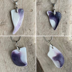 May include: Four silver necklaces each featuring a unique pendant. The pendants are made of a white and purple marbled material. The pendants have different shapes, including a heart and an asymmetrical design.
