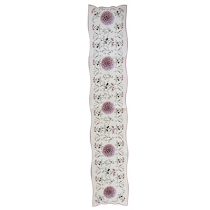 May include: A long, rectangular white scarf featuring a repeating pattern of large, soft purple dahlia flowers interspersed with smaller, delicate botanical illustrations of green leaves and pink floral sprigs, finished with a scalloped pink edge.