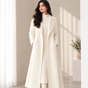 May include: A long, cream-coloured wool coat with wide lapels and deep side pockets, worn over a matching cream-coloured ribbed knit dress that reaches the mid-calf, paired with cream-coloured knee-high boots with a block heel.