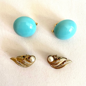 Könnte beinhalten: Ein Paar Ohrringe mit einem hellblauen runden Design und ein Paar goldene Ohrringe mit einem Perlen- und einem kleinen Diamanten-Akzent.