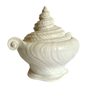 Pu&ograve; includere: Piatto da portata in ceramica bianca a forma di conchiglia, con coperchio. Il piatto &egrave; decorato con linee in rilievo e un motivo a spirale.