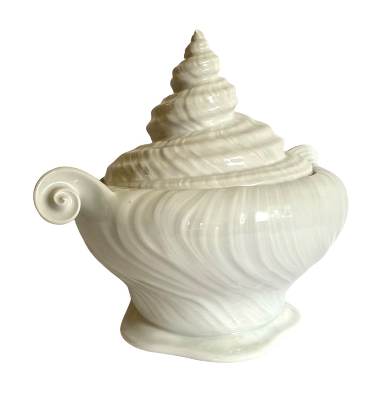 Pu&ograve; includere: Piatto da portata in ceramica bianca a forma di conchiglia, con coperchio. Il piatto &egrave; decorato con linee in rilievo e un motivo a spirale.