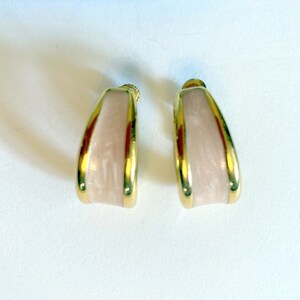 Könnte beinhalten: Ein Paar goldfarbene Ohrclips mit einem rechteckigen, pinkfarbenen, strukturierten Design.