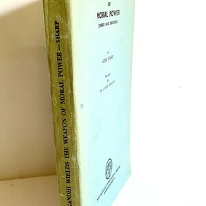 May include: A vintage book titled "Gandhi Wields the Weapon of Moral Power" by Gene Sharp. The book has a light green cover with black text. The spine shows the title and author. The book's edges show signs of wear.