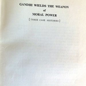 May include: Open book page with the title "GANDHI WIELDS THE WEAPON of MORAL POWER" in black text. Below the title is the text "[THREE CASE HISTORIES]" in black. The page is white.
