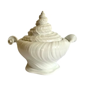 Pu&ograve; includere: Piatto da portata in ceramica bianca a forma di conchiglia, con coperchio. Il piatto &egrave; decorato con linee in rilievo e un motivo a spirale.
