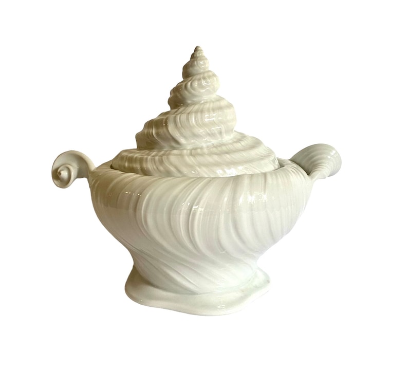 Pu&ograve; includere: Piatto da portata in ceramica bianca a forma di conchiglia, con coperchio. Il piatto &egrave; decorato con linee in rilievo e un motivo a spirale.
