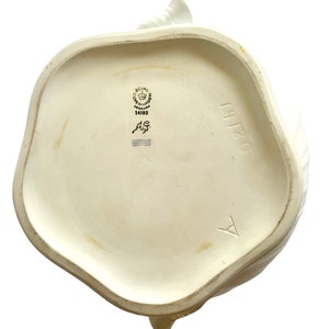 Pu&ograve; includere: Teiera in ceramica bianca con un motivo floreale. La parte inferiore della teiera presenta il logo Royal Copenhagen e il numero 14180.