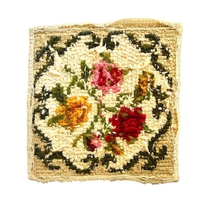 Könnte beinhalten: Quadratischer, cremefarbener Teppich mit floralem Design. Der Teppich zeigt einen zentralen Blumenstrauß aus roten, rosa und gelben Blumen, umgeben von einem grünen, blattreichen Rand. Die Kanten sind mit einer cremefarbenen Bordüre versehen.