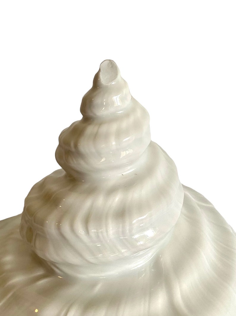 Pu&ograve; includere: Scultura di conchiglia di ceramica bianca con un design a spirale. La conchiglia &egrave; liscia e lucida.