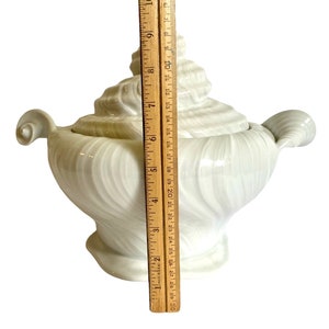 Pu&ograve; includere: Piatto da portata in ceramica bianca a forma di conchiglia, con coperchio. Il piatto &egrave; alto circa 18 cm e presenta un motivo a spirale.