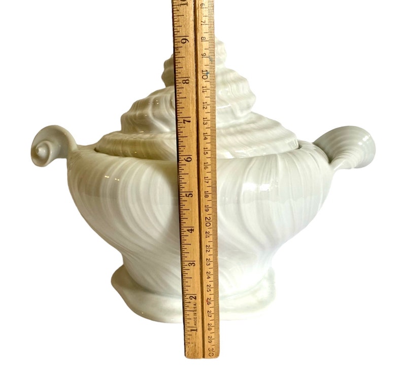 Pu&ograve; includere: Piatto da portata in ceramica bianca a forma di conchiglia, con coperchio. Il piatto &egrave; alto circa 18 cm e presenta un motivo a spirale.