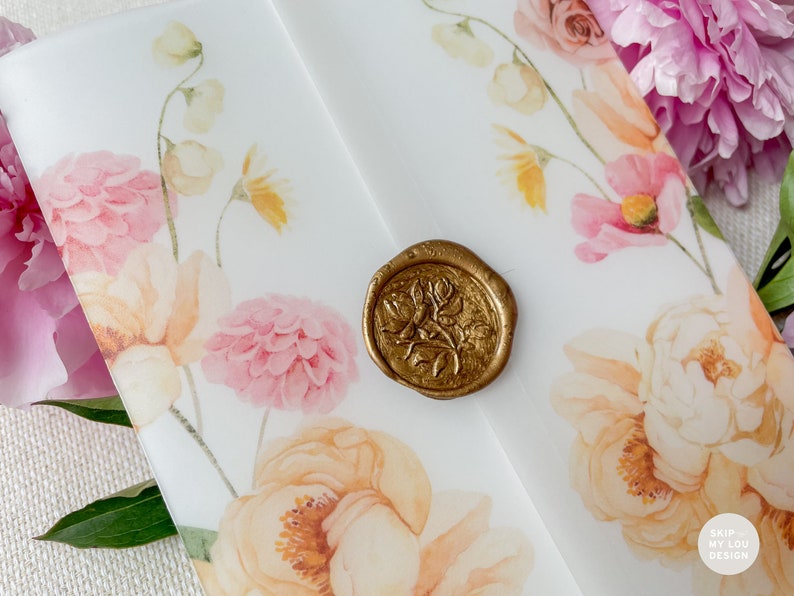 May include: A white envelope with a floral design and a gold wax seal. The flowers are pink, yellow, and white. The seal has a floral design.