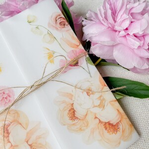 May include: A white envelope with a floral design featuring pink and yellow flowers. The envelope is tied with a brown twine bow. The text "SKIP MY LOU DESIGN" is printed in the bottom right corner.
