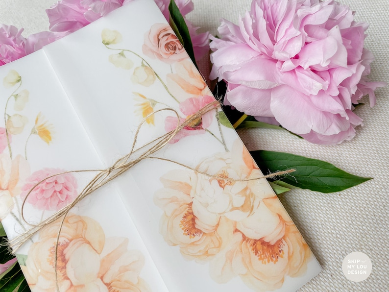 May include: A white envelope with a floral design featuring pink and yellow flowers. The envelope is tied with a brown twine bow. The text "SKIP MY LOU DESIGN" is printed in the bottom right corner.