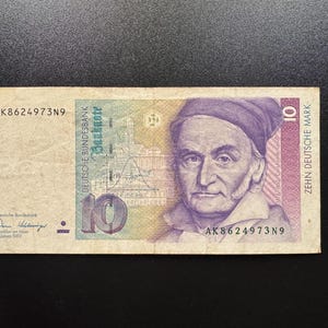 Może przedstawiać: Zabytkowy banknot 10 marek niemieckich z portretem Carla Friedricha Gaussa, wykresem krzywej dzwonowej oraz napisem Deutsche Bundesbank, Banknote, Zehn Deutsche Mark i numerem seryjnym AK8624973N9, datowany na 2 stycznia 1969 roku.