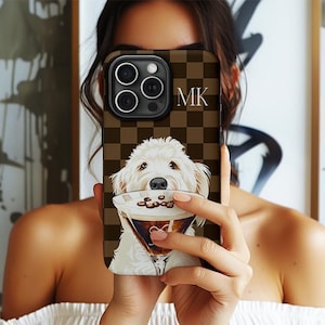 Puede incluir: Una funda de teléfono a cuadros marrones y beige con una ilustración de un perro blanco sosteniendo una copa de martini. La funda muestra las iniciales "MK" en blanco. El gráfico del perro está centrado en la funda.