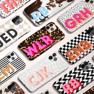 May include: A collection of phone cases with various patterns and initial letters. Designs include cow print, leopard print, polka dots, stripes, and geometric shapes. The letters are in bold, colorful fonts, with a 3D effect.