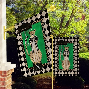 May include: Two garden flags with a black and white checkered background. The flags feature a cheetah with a bow and an umbrella. The larger flag has the letter "N" on it.