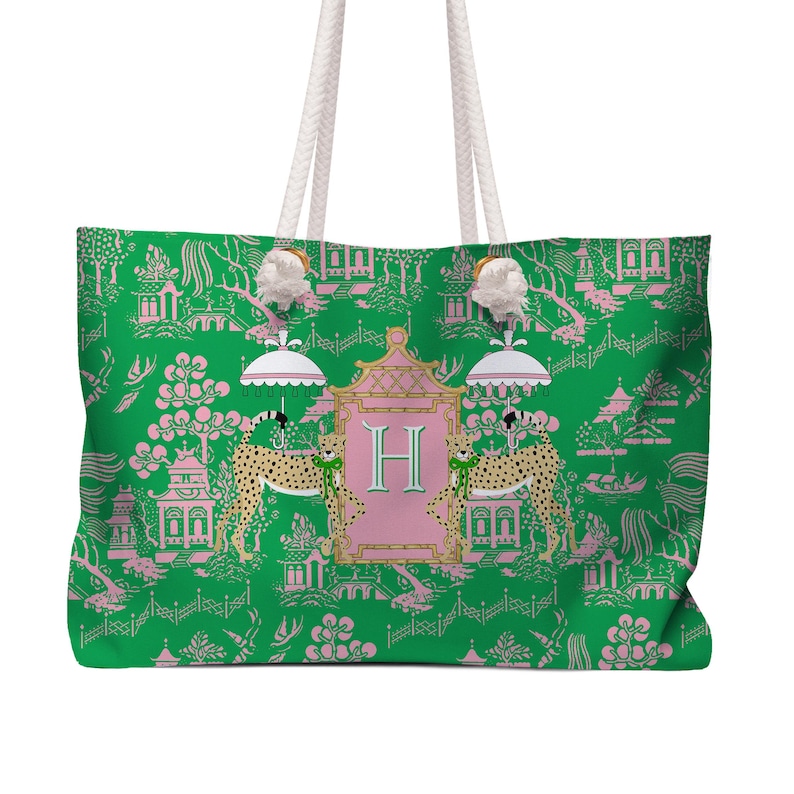 May include: A large green tote bag with white rope handles. The bag features a pink and green Asian-inspired pattern with cheetahs, pagodas, and the letter "H". The bag has a white background.