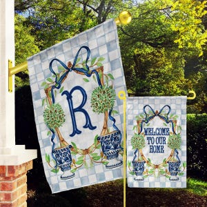 May include: Two garden flags with a blue and white checkered background. The larger flag features a blue letter "R" surrounded by green topiary trees in blue and white urns. The smaller flag says "Welcome to our home" with the same design elements.