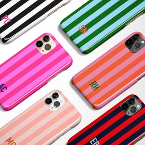 May include: A collection of colorful phone cases with striped patterns. Cases feature pink, orange, blue, green, and red stripes. Each case has a different initial in a contrasting color. The cases are designed for a smartphone.