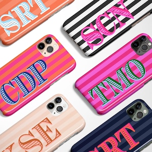 May include: A collection of personalized phone cases with various striped patterns in orange, pink, black, and navy blue. Each case features a different set of initials in bold, contrasting colors, such as blue, green, and pink. The cases are designed for a smartphone.