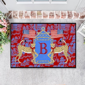 May include: Red doormat with a blue and gold crest featuring the letter "B". Two cheetahs flank the crest, and two American flags are displayed above. The background is a red and blue chinoiserie pattern.