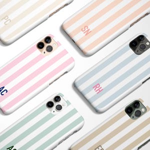 May include: A collection of personalized phone cases with a striped design. The cases are in various pastel colors, including pink, blue, green, and beige, with white stripes. Each case features initials in a contrasting color.