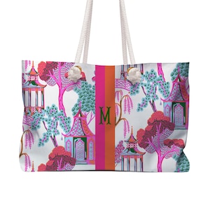 May include: White tote bag with a colorful Asian-inspired pattern featuring pagodas, trees, and floral elements in pink, teal, and green. The bag has a vertical stripe with the letter "M" and rope handles.