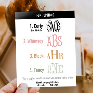 May include: A white rectangular card titled FONT OPTIONS displaying four styles: 1. Curly with black script initials, 2. Whimsey with pink serif initials, 3. Block with orange serif initials, and 4. Fancy with green outlined initials, plus text instructions.