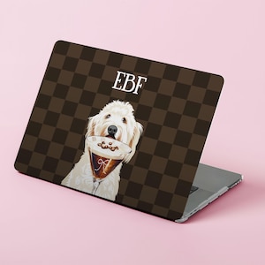 Könnte beinhalten: Laptop-Hülle mit einem braunen Schachbrettmuster und einer Illustration eines weißen Hundes, der ein Kaffeegetränk hält. Die Initialen "EBF" sind weiß. Der Hintergrund ist rosa.