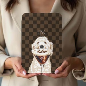 Puede incluir: Funda para tableta a cuadros marrones y beige con una ilustración de un perro blanco sosteniendo un martini de café. La copa de martini tiene granos de café y la letra "A". Las iniciales "ENC" están en la parte superior.