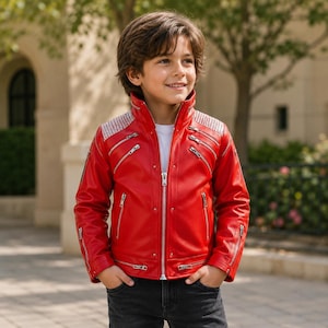 Könnte beinhalten: Eine leuchtend rote Jacke mit hohem Kragen, mehreren silberfarbenen Metallreißverschlüssen an Brust und Ärmeln sowie strukturierten silbernen Schulterpartien. Die Jacke wird über einem weißen Shirt und einer dunkelgrauen Jeans getragen.
