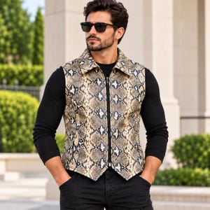 May include: A sleeveless waistcoat featuring a tan, black, and white snakeskin pattern. The garment has a pointed collar, a full-length front zip fastening, and a structured fit. It is worn over a solid black long-sleeved shirt and black trousers.