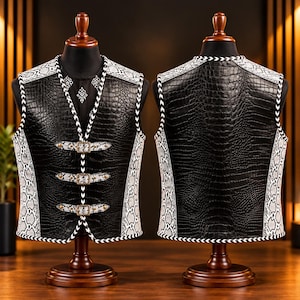 Op de afbeelding: Een mouwloos vest met een zwart krokodil-textuurpatroon op de voor- en achterkant, geaccentueerd door witte en grijze slangenleer-patroon zijpanelen en biezen. De voorkant bevat drie horizontale banden met metalen gespen.