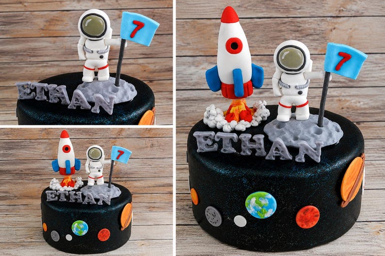 以下が含まれることがあります： 宇宙をテーマにしたフォンダンフィギュアで飾られた黒いケーキ。白いロケット、数字の7が書かれた青い旗を持つ宇宙飛行士、ETHANという文字を形作る岩のような質感の灰色の文字が含まれています。側面には平らな惑星の装飾が施されています。
